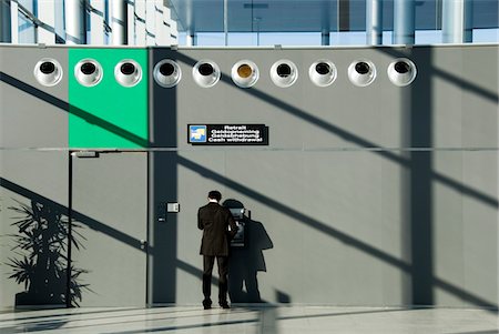 Man using cash machine at airport, rear view Stock Photo - Premium Royalty-Free, Code: 6108-05860601