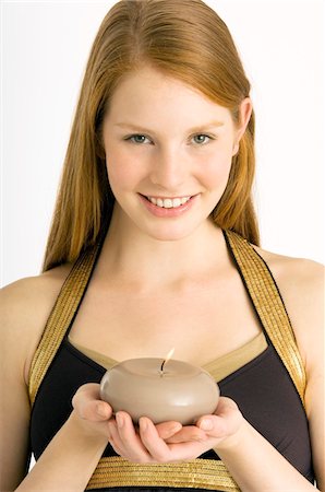 Portrait of a young woman holding a burning candle and smiling Stock Photo - Premium Royalty-Free, Code: 6108-05860628