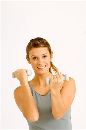 Portrait of a young woman exercising with dumbbells Stock Photo - Premium Royalty-Free, Code: 6108-05860864