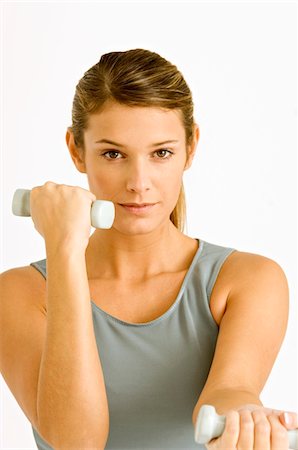 Portrait of a young woman exercising with dumbbells Stock Photo - Premium Royalty-Free, Code: 6108-05860889