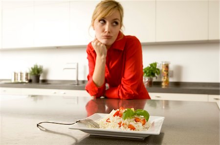 disgust - Plate of rice in front of a young woman leaning against a kitchen counter Stock Photo - Premium Royalty-Free, Code: 6108-05860830