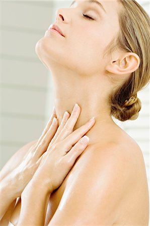 Close-up of a young woman applying moisturizer on her neck Stock Photo - Premium Royalty-Free, Code: 6108-05860910