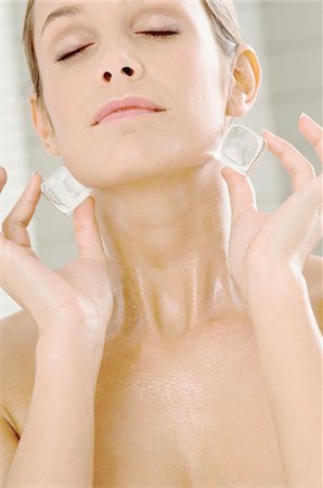 Close-up of a young woman rubbing ice cubes on her neck Stock Photo - Premium Royalty-Free, Code: 6108-05860924