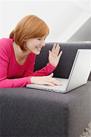Young woman using a laptop and smiling Stock Photo - Premium Royalty-Free, Code: 6108-05861044