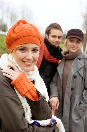 Close-up of a young woman smiling with her friends standing in the background Stock Photo - Premium Royalty-Free, Code: 6108-05861096