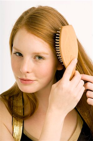 Portrait of a young woman brushing her hair Stock Photo - Premium Royalty-Free, Code: 6108-05861002