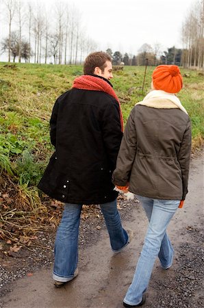 Rear view of a young couple walking on a dirt road Stock Photo - Premium Royalty-Free, Code: 6108-05861141