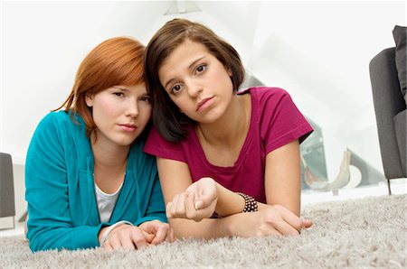 simsearch:6108-05863386,k - Portrait of two young women lying on a carpet and looking serious Stock Photo - Premium Royalty-Free, Code: 6108-05861172