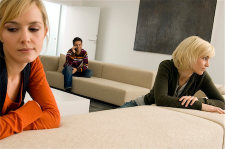 simsearch:6108-05863386,k - Two young women thinking with a young man sitting in the background Stock Photo - Premium Royalty-Free, Code: 6108-05861114