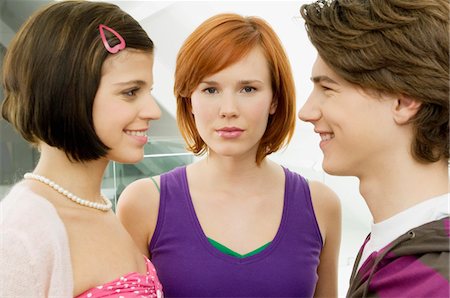 Side profile of a teenage boy smiling with two young women Stock Photo - Premium Royalty-Free, Code: 6108-05861218