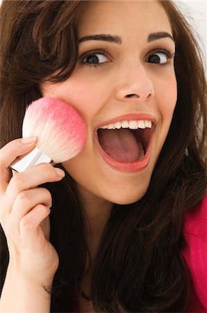 Portrait of a woman applying blusher on her face Stock Photo - Premium Royalty-Free, Code: 6108-05862297