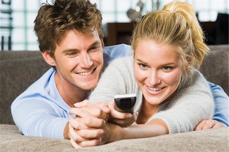 simsearch:6108-05858292,k - Couple holding a remote control and smiling Stock Photo - Premium Royalty-Free, Code: 6108-05862333