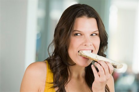 self indulgence - Close-up of a woman eating a bread Stock Photo - Premium Royalty-Free, Code: 6108-05862415