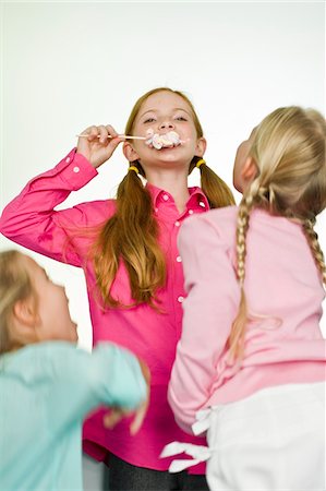 simsearch:6108-05865577,k - Girl eating a lollipop and her friends looking at her Stock Photo - Premium Royalty-Free, Code: 6108-05862664