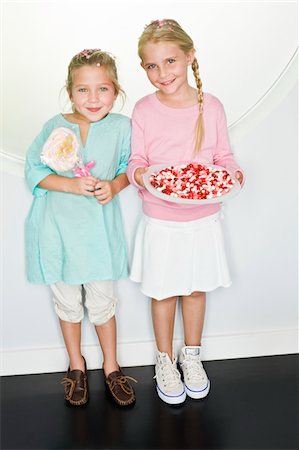 Girl holding a plate of jelly beans with her friend standing beside her Stock Photo - Premium Royalty-Free, Code: 6108-05862668
