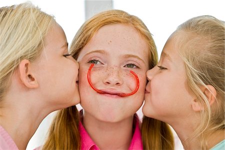 simsearch:6108-05865577,k - Close-up of two girls kissing their friend Stock Photo - Premium Royalty-Free, Code: 6108-05862669