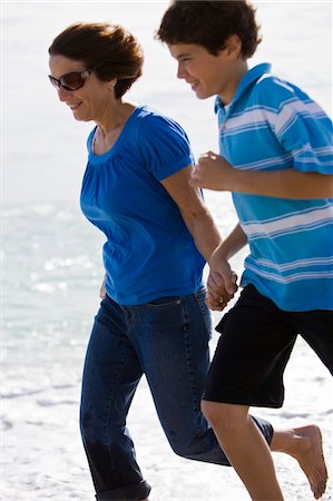 pictures of woman running with short hair - Woman running on the beach with her grandson Stock Photo - Premium Royalty-Free, Code: 6108-05862619