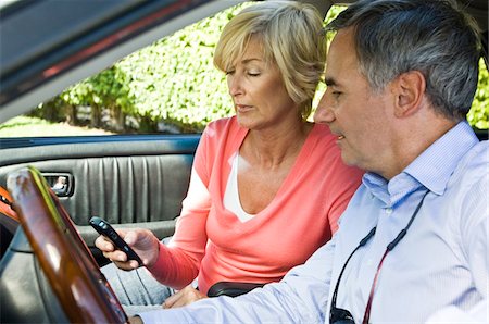 Couple in a car and text messaging Stock Photo - Premium Royalty-Free, Code: 6108-05862796