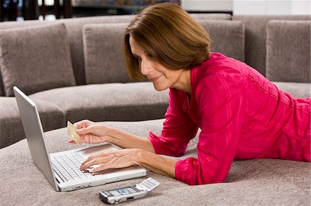 ecommerce - Woman holding a credit card and working on a laptop Stock Photo - Premium Royalty-Free, Code: 6108-05862868