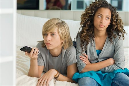 Teenage boy watching television with a girl sitting beside him Stock Photo - Premium Royalty-Free, Code: 6108-05862892