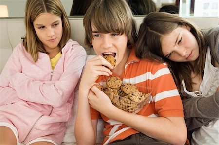 simsearch:6108-05863846,k - Garçon mangeant des cookies au chocolat avec deux filles à côté de lui Photographie de stock - Premium Libres de Droits, Code: 6108-05862971