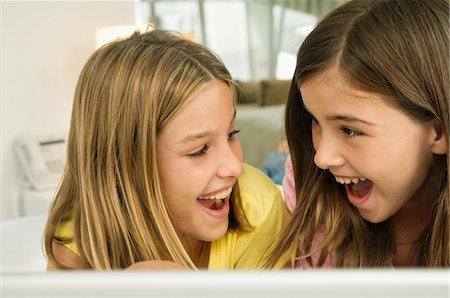 Close-up of two girls smiling at each other with a surprise Stock Photo - Premium Royalty-Free, Code: 6108-05862981