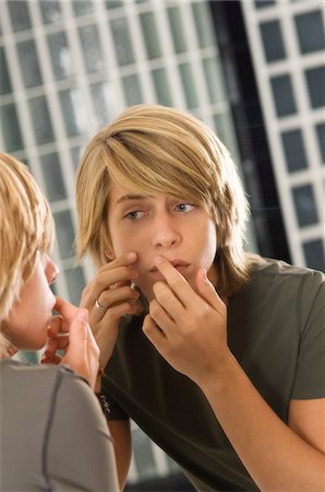 Teenage boy looking at himself in a mirror Stock Photo - Premium Royalty-Free, Code: 6108-05862916