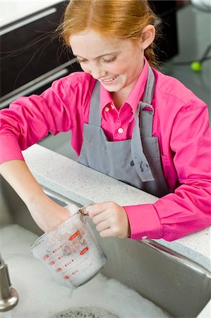 Close-up of a girl washing a measuring jug at a sink Stock Photo - Premium Royalty-Free, Code: 6108-05863019