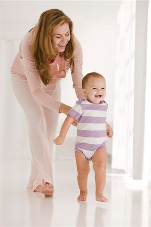 emotional images of mother holding baby - Woman helping her daughter to walk Stock Photo - Premium Royalty-Free, Code: 6108-05863211