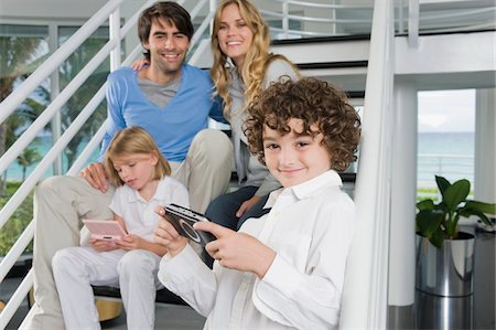 simsearch:6108-05863411,k - Parents sitting on steps with their children playing video games Stock Photo - Premium Royalty-Free, Code: 6108-05863404