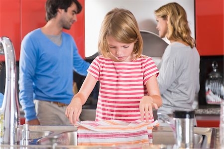 simsearch:6108-05863411,k - Girl holding dish cloth with her parents standing in the background Stock Photo - Premium Royalty-Free, Code: 6108-05863417