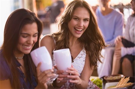 simsearch:6108-05861651,k - Two women enjoying drink with their friends in the background Stock Photo - Premium Royalty-Free, Code: 6108-05863729