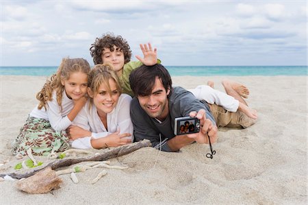 simsearch:6108-05863846,k - Homme qui prend une photo de sa famille avec un appareil photo numérique sur la plage Photographie de stock - Premium Libres de Droits, Code: 6108-05864056