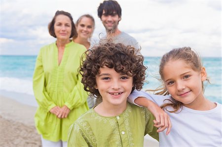 simsearch:6108-05858260,k - Boy and a girl smiling with their family behind them on the beach Stock Photo - Premium Royalty-Free, Code: 6108-05864064