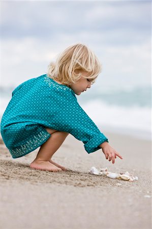 Girl playing with shells on the beach Stock Photo - Premium Royalty-Free, Code: 6108-05864080