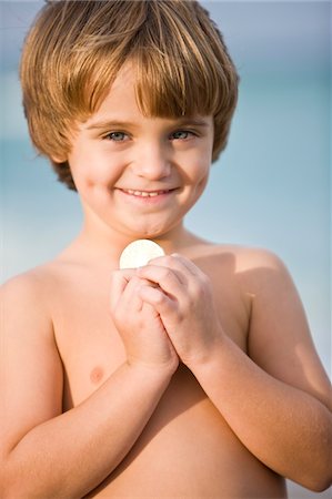 Portrait d'un garçon tenant une pièce de monnaie et souriant Photographie de stock - Premium Libres de Droits, Code: 6108-05864090