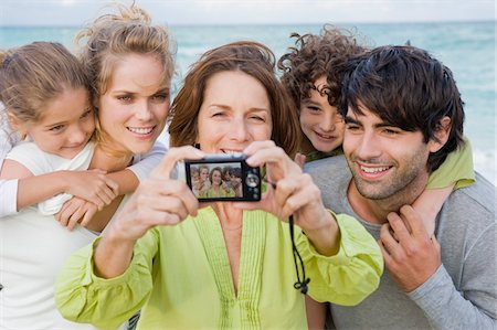piggyback brothers - Woman taking a picture of her family with a digital camera Stock Photo - Premium Royalty-Free, Code: 6108-05864017