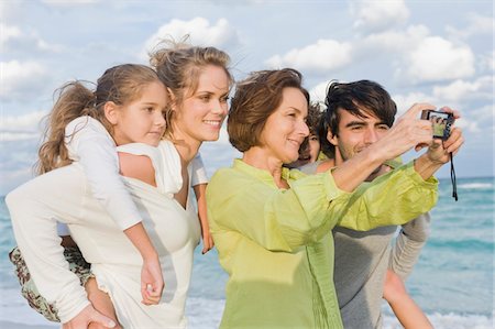 daughter piggyback at beach - Woman taking a picture of her family with a digital camera Stock Photo - Premium Royalty-Free, Code: 6108-05864030