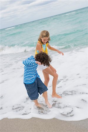 Boy playing with a girl on the beach Stock Photo - Premium Royalty-Free, Code: 6108-05864145