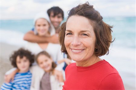 Woman smiling with her family on the beach Stock Photo - Premium Royalty-Free, Code: 6108-05864146