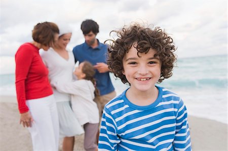 simsearch:6108-05858128,k - Boy smiling with his family standing behind him on the beach Stock Photo - Premium Royalty-Free, Code: 6108-05864177