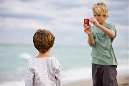 Boy taking his brother's picture with a digital camera Stock Photo - Premium Royalty-Free, Code: 6108-05864105