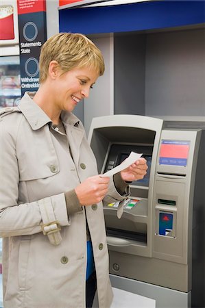 simsearch:6108-05860554,k - Woman reading a transaction slip at an ATM and smiling Stock Photo - Premium Royalty-Free, Code: 6108-05864532