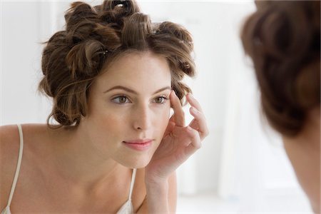 Woman examining her face in the mirror Stock Photo - Premium Royalty-Free, Code: 6108-05864678