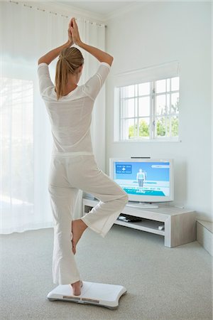 Woman doing yoga in front of television Stock Photo - Premium Royalty-Free, Code: 6108-05864821