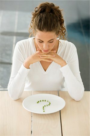 question mark - Woman sitting at a table with peas in question mark shape on a plate Stock Photo - Premium Royalty-Free, Code: 6108-05864955