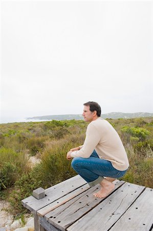 simsearch:6108-05859747,k - Man crouching on a boardwalk and thinking Stock Photo - Premium Royalty-Free, Code: 6108-05865070