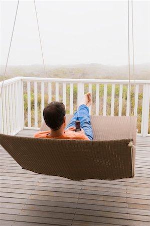 simsearch:6108-05857751,k - Man using a mobile phone on a porch swing Stock Photo - Premium Royalty-Free, Code: 6108-05865021