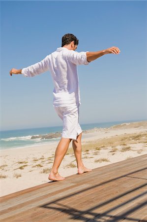 Man walking on a boardwalk on the beach Stock Photo - Premium Royalty-Free, Code: 6108-05865022