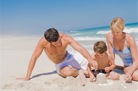 sand castle - Family making a sand castle on the beach Stock Photo - Premium Royalty-Free, Code: 6108-05865165